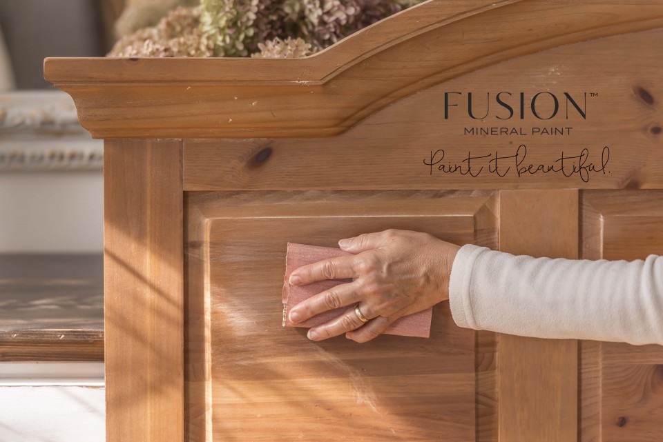 The headboard is being sanded, leaving light scratches on the surface.