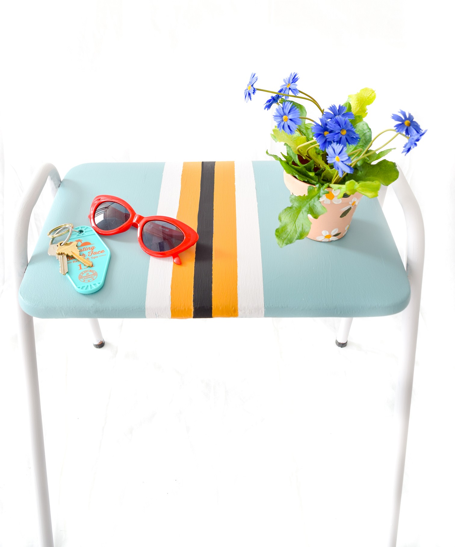 Blue and yellow stool with red glasses and plant on it