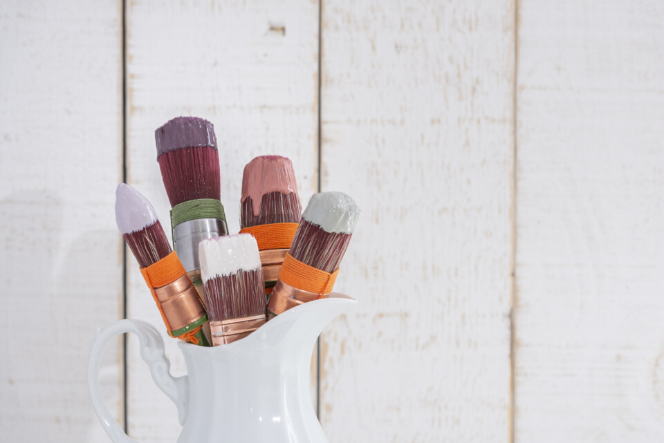 Jug of brushes with paint dripping on them