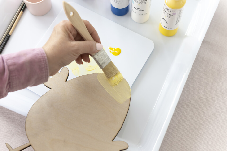 painting wood cut out of chicken with yellow paint