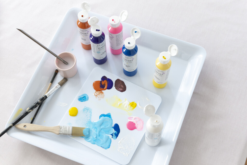 open pots of paint on a tray, brushes and brushstrokes of colour