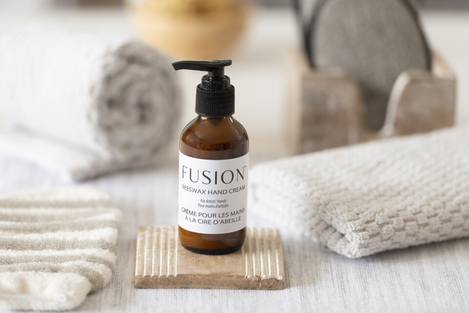 Fusion beeswax hand cream, staged on a coaster and  beside a white hand towel