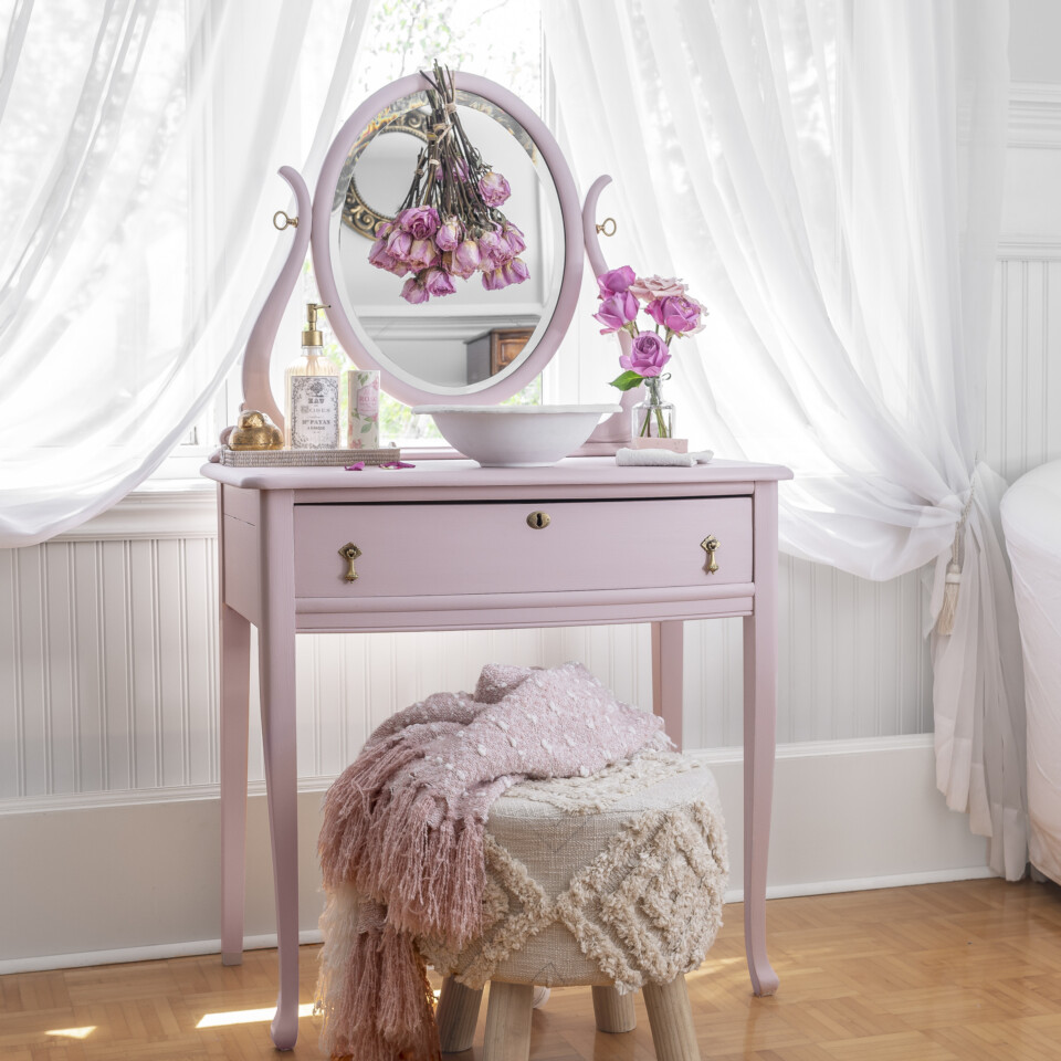 Painted and staged vanity with white stool, roses in clear vase & pink throw blanket
