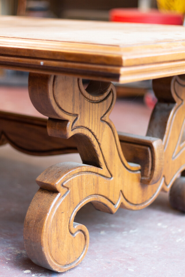 Zoomed in photo of the coffee table emphasis on the wooden legs that have an intricate design