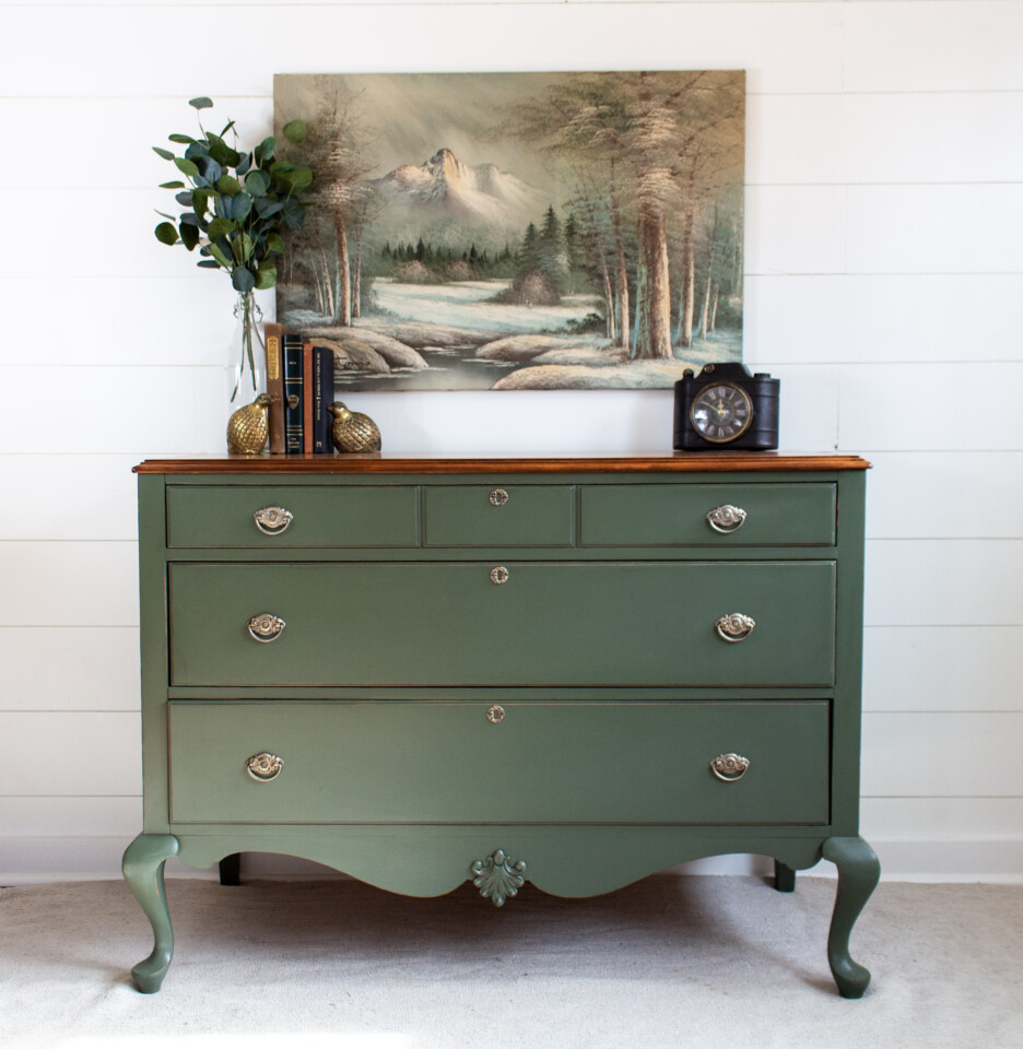 Staged dresser painted in bayberry, vintage clock and plant sitting on top of dresser & art hanging on the wall above