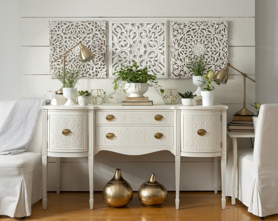 White dresser staged with gold lamps and decor, plants in white pots