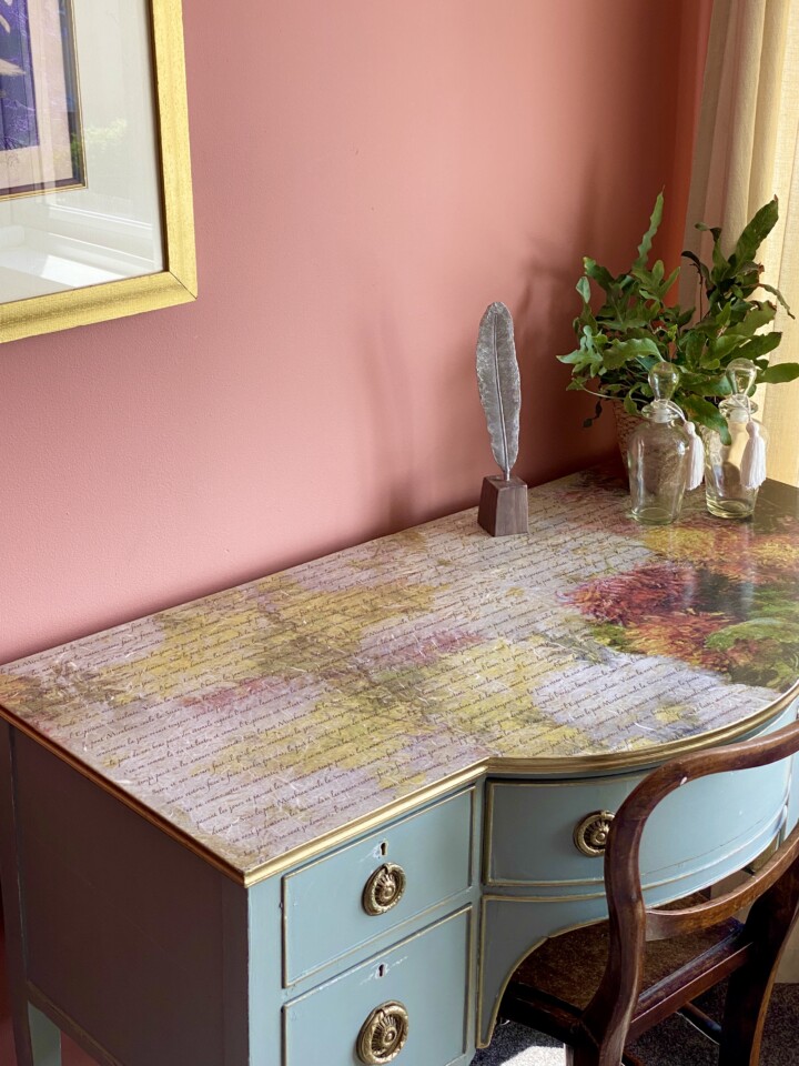 Top angle view of desk with decoupage, staged with vases and feather pen