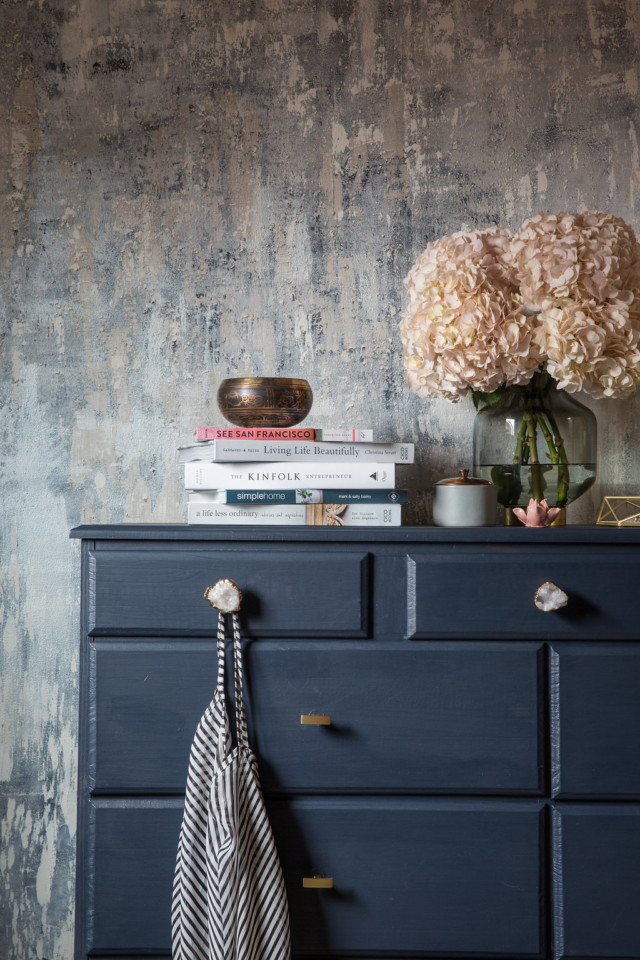 Staged midnight blue dresser with light pink flowers and a stack of books