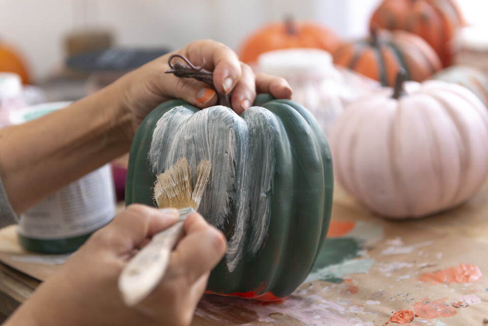 Painting a green pumpkin with white paint