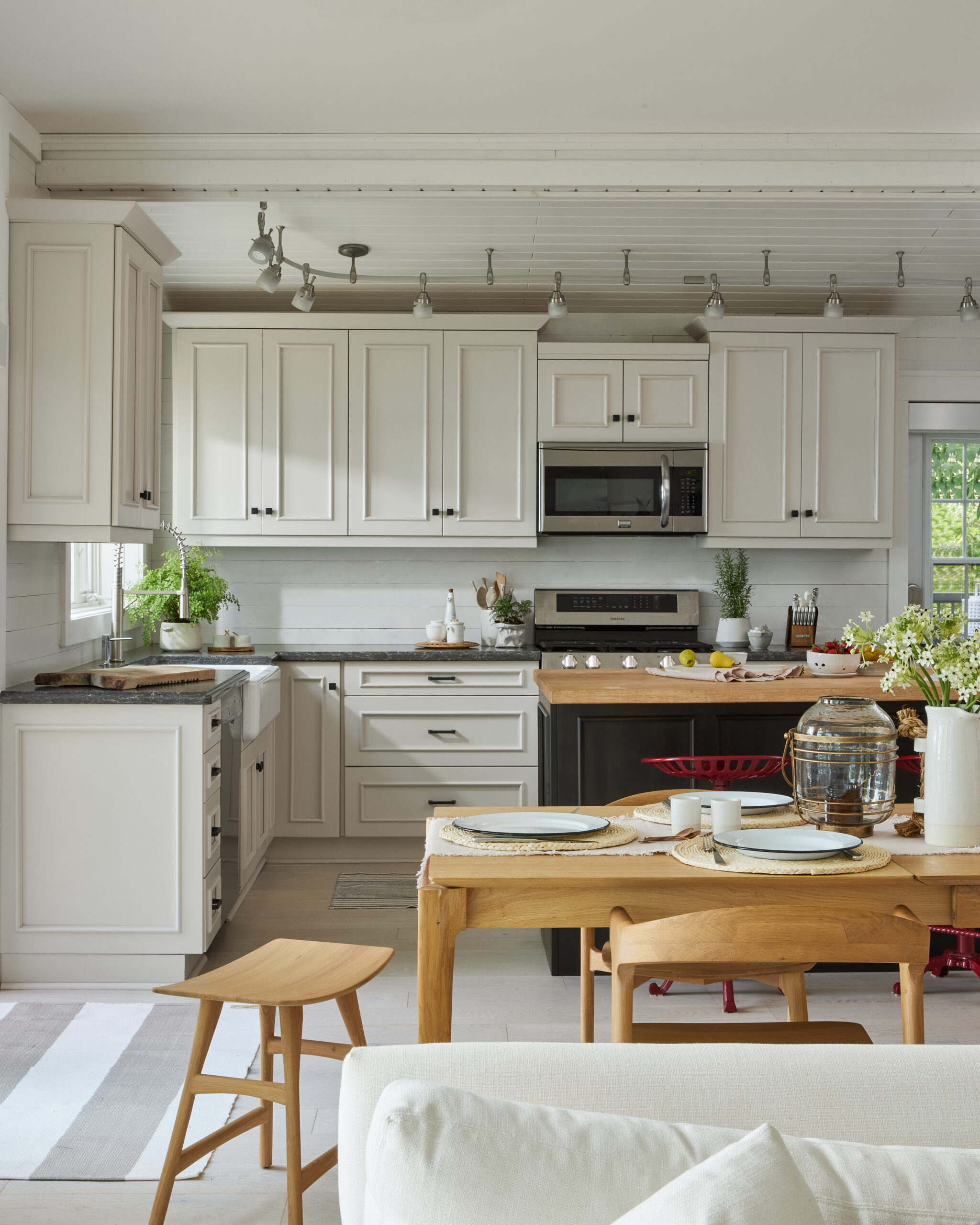 Kitchen with white cabinets, dark grey island and red stools. Staged with fresh fruit & a recipe book on the island.