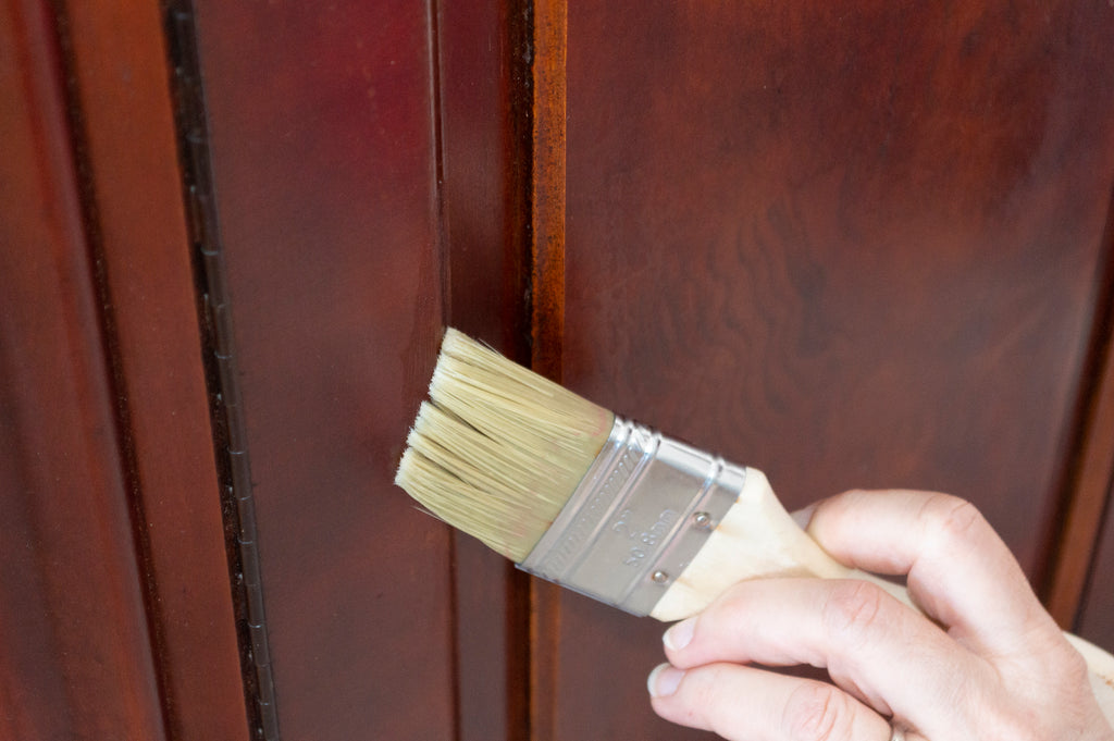 brushing on beeswax finish to start the Chippy Chic Bar Cabinet Makeover